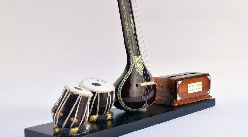 Model of a sitar, tabla, and other instruments on a stand with a white background