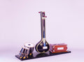 Model of a sitar, tabla, and other instruments on a stand with a light purple background