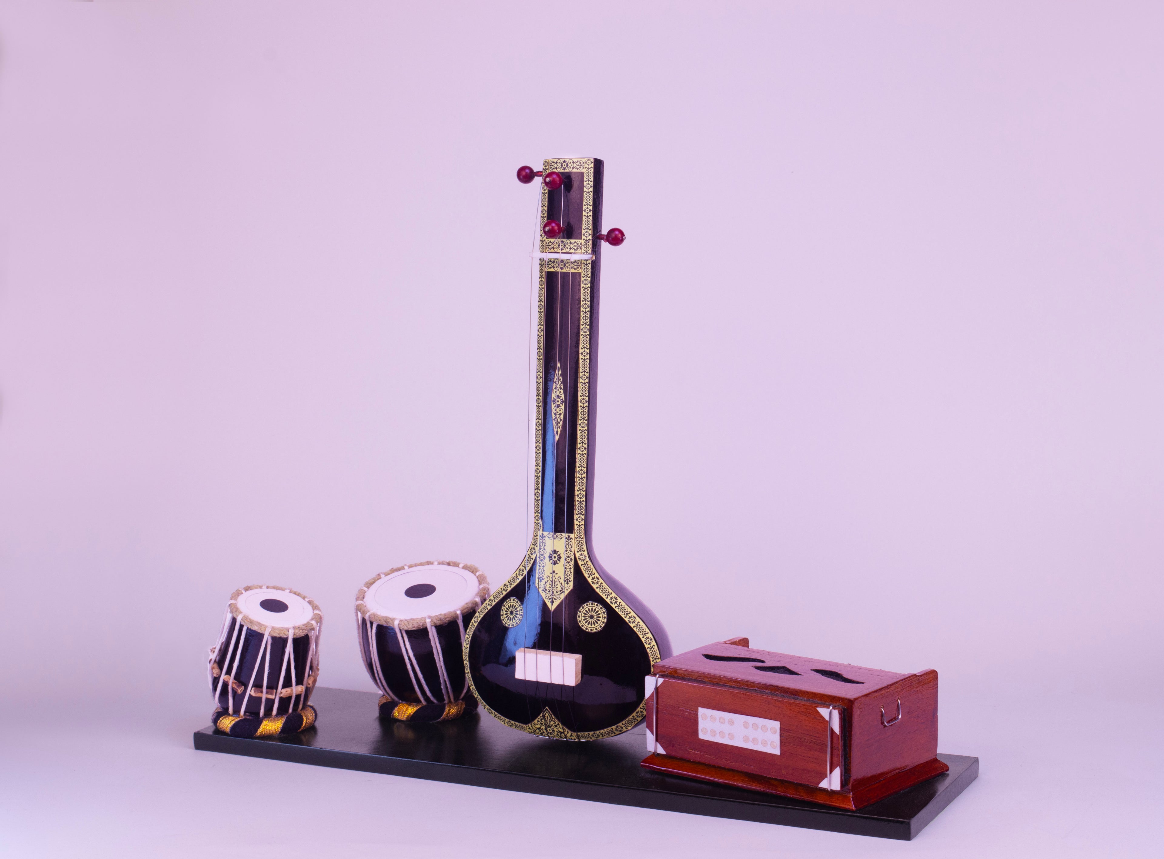 Model of a sitar and two small drums on a stand with a purple background